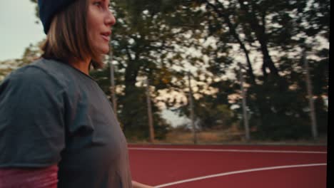 a girl receives a basketball, catches it and throws it into the basketball hoop