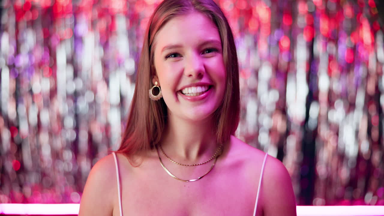 행복한 젊은 여성이 밤의 설정에서 카메라에 미소 짓고 있습니다.