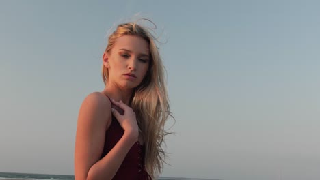 Arc-shot-of-a-blonde-posing-on-a-beach