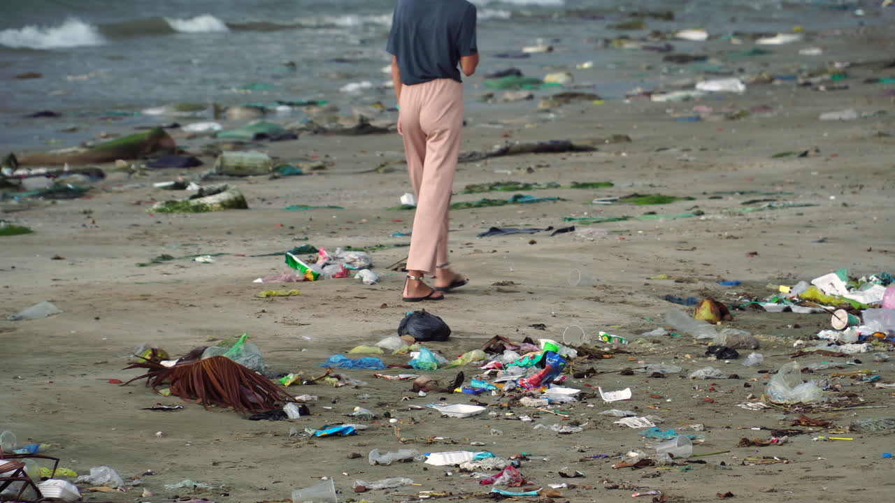 Girl Followed By A Dog Walking On The Beach With Trash