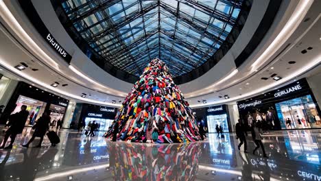 a vibrant mall interior with a colorful art installation. shoppers walk around the mall. the mall