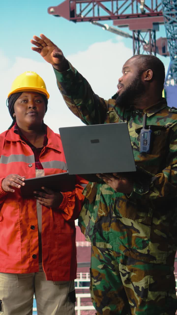 Vertical video Military personnel on offshore rig analyzing tactical data on laptop