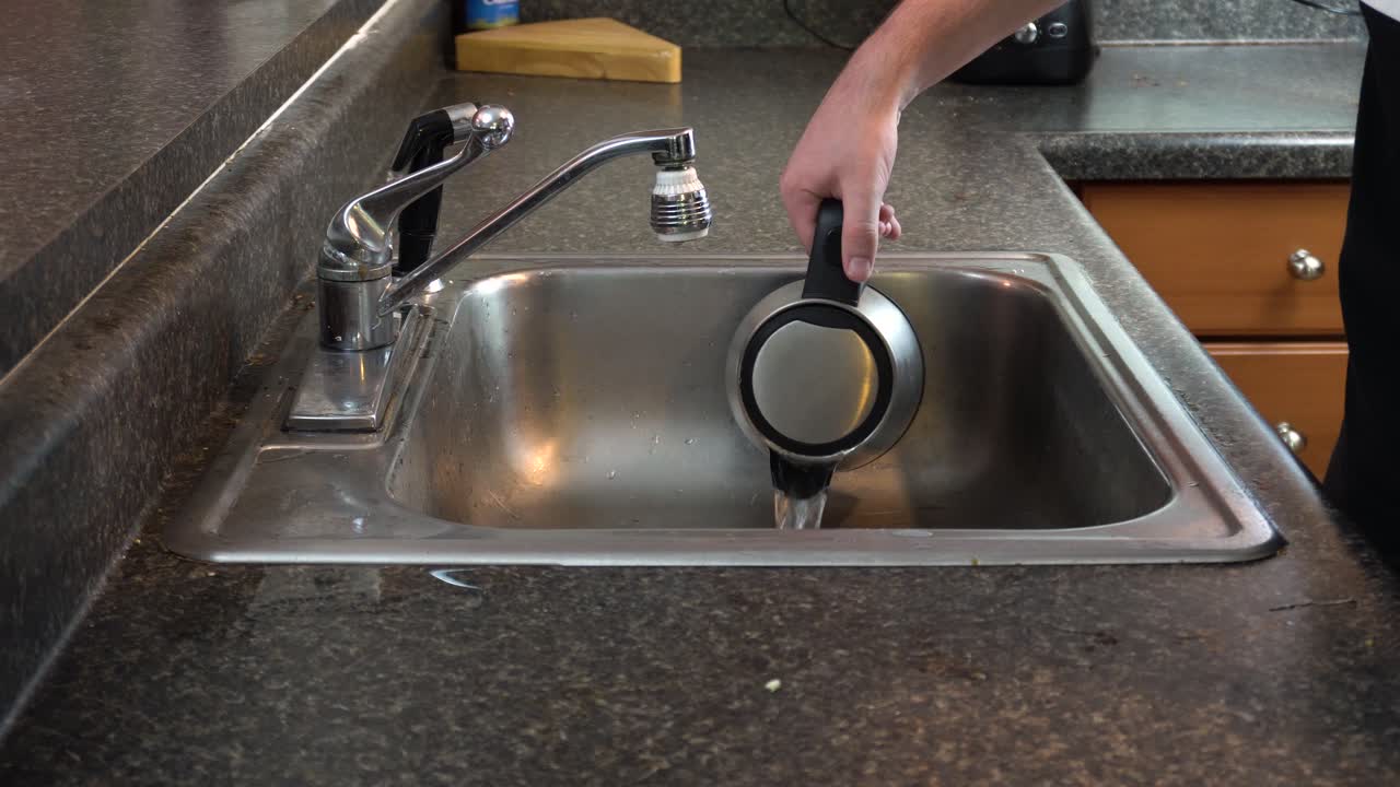 Imagen de un hervidor de té o café vaciándose en un fregadero de cocina.
