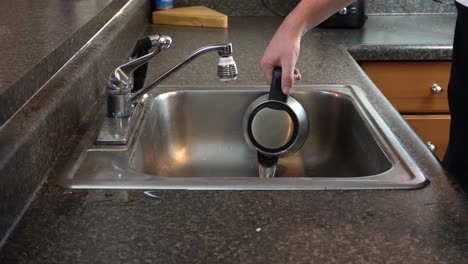 Shot-of-a-tea-or-coffee-kettle-being-dumped-out-into-a-kitchen-sink