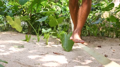 Medium-shot-of-a-man-slack-lining-in-a-tropical-jungle-environment