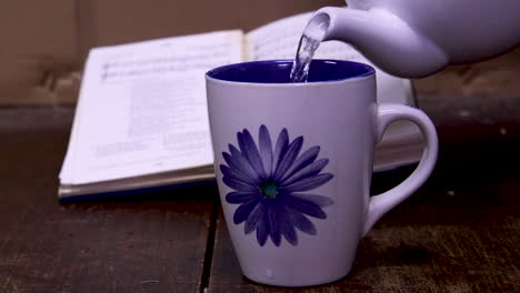 vertiendo una taza de café con un libro fuera de enfoque en el fondo