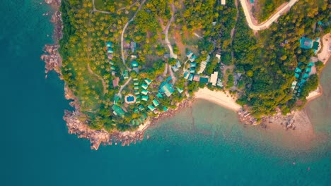 4k aerial drone push forward shot of salad beach on koh phangan in thailand with fishing boats, teal water, coral, and green jungles