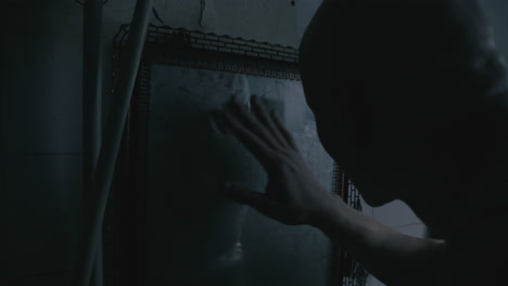 pale bald skinny man looks into the mirror in the creepy old bathroom at night