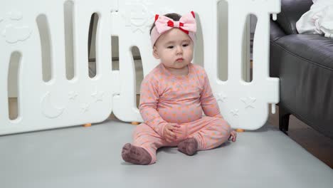 Baby-Girl-Sitting-On-The-Floor-Inside-A-Playpen-In-The-Room---close-up