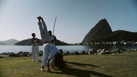 people practicing capoeira outdoors with sugarloaf mountain in rio de janeiro