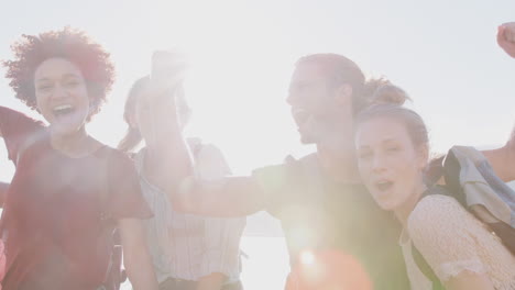 portrait of young friends hiking celebrating reaching the peak of coastal cliff