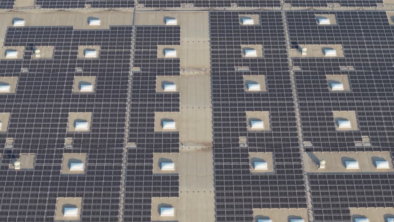 A drone aerial video showing an industrial building roof covered with solar panels. The clean geometric layout of the panels highlights the structure’s modern design and commitment to renewable energy