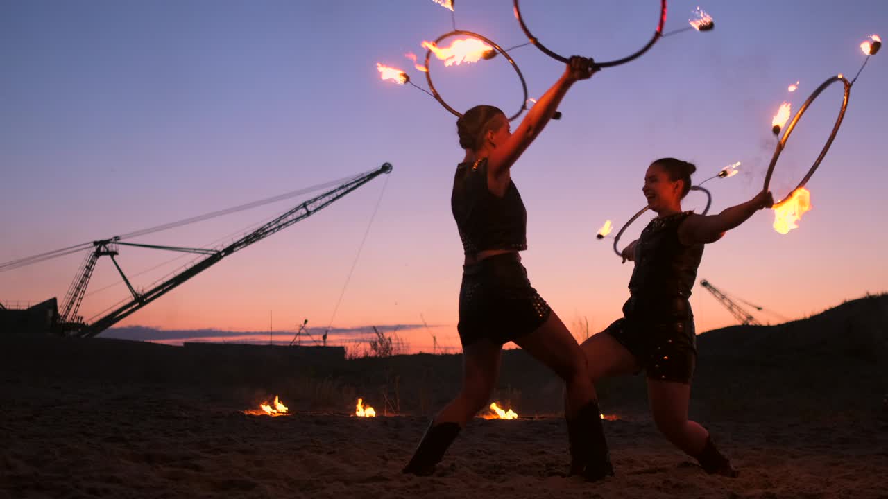 Artisti professionisti eseguono uno spettacolo di fuoco a un festival estivo sulla sabbia al rallentatore. Acrobati circensi lavorano con il fuoco di notte sulla spiaggia
