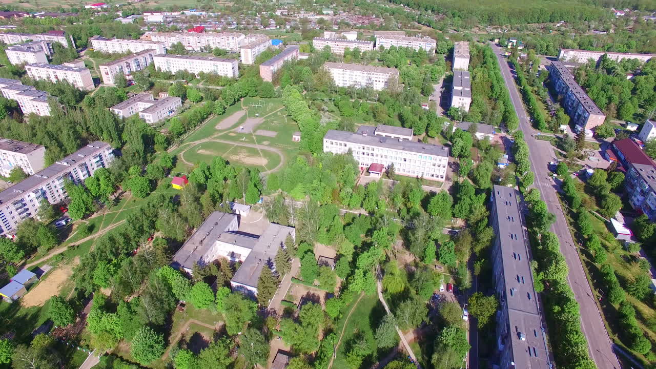 Blocks of flats built in rectangular and full of green trees. Aerial view on the residential areas on beautiful sunny day.
