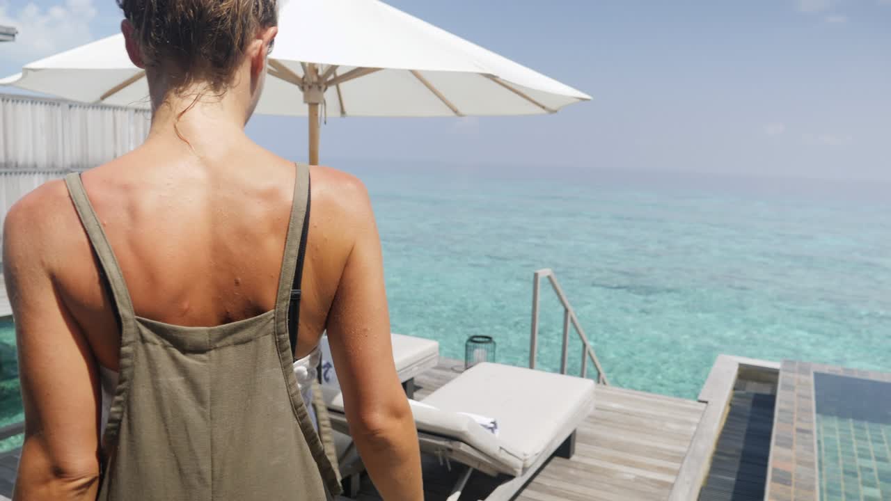 una mujer joven tira de las cortinas de la habitación del hotel y sale.