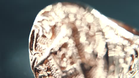 a macro detailed tilt up shot of a golden textured freemasons ring, on a rotating stand, illuminati symbol, professional studio lighting, 4k video