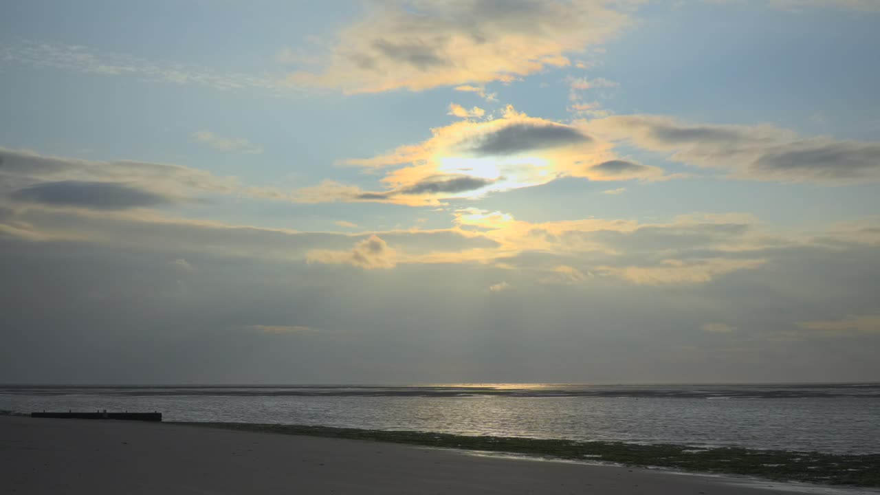 rayos de luz solar que se mueven a través del mar hasta que el sol se mueve detrás de las nubes antes de la puesta del sol