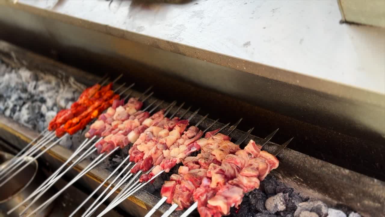 close-up shot capturing cooking traditional-style barbecue in the Altay region of Central Asia. Chef uses a brush to baste lamb and seasoned meat skewers with sauce, preparing halal street food