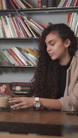 una mujer joven bebiendo café en una cafetería.