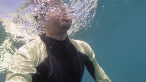 freediver looking into camera on the surface , shot from below