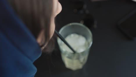 high angle view of female drink cold lemonade with ice cubes with straw