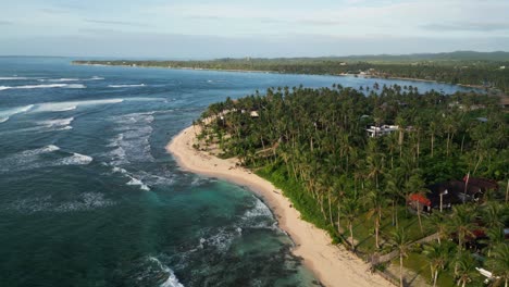 Aerial-view-of-waves-hitting-Daku-Island-white-sand-beach,-Philippines