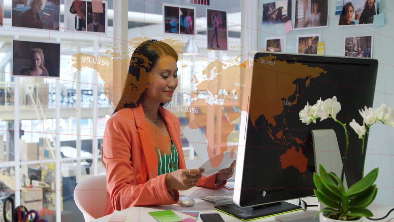 animación de números sobre el mapa del mundo contra la diseñadora gráfica caucásica sosteniendo una muestra de color.