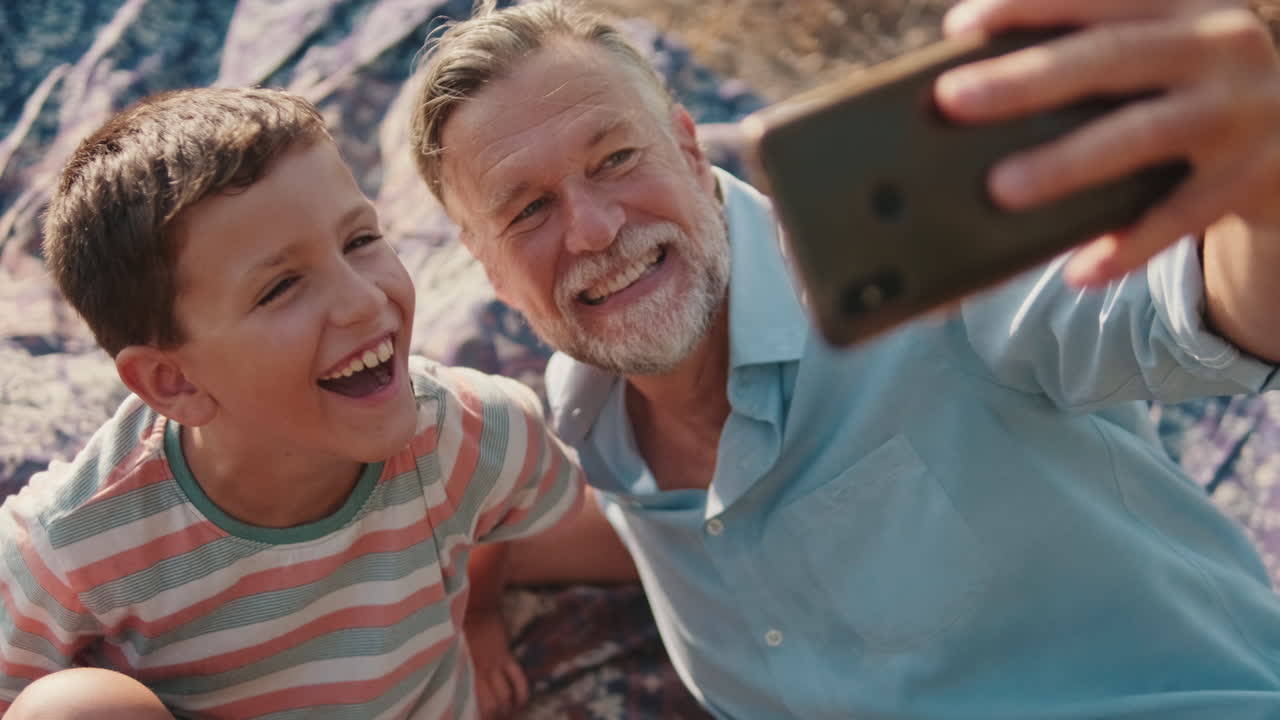 Happy Grandfather and Grandson Taking a Selfie Together Outdoors