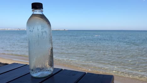 Close-up-of-condensation-cold-water-bottle-against-the-background-of-the-Greek-sea