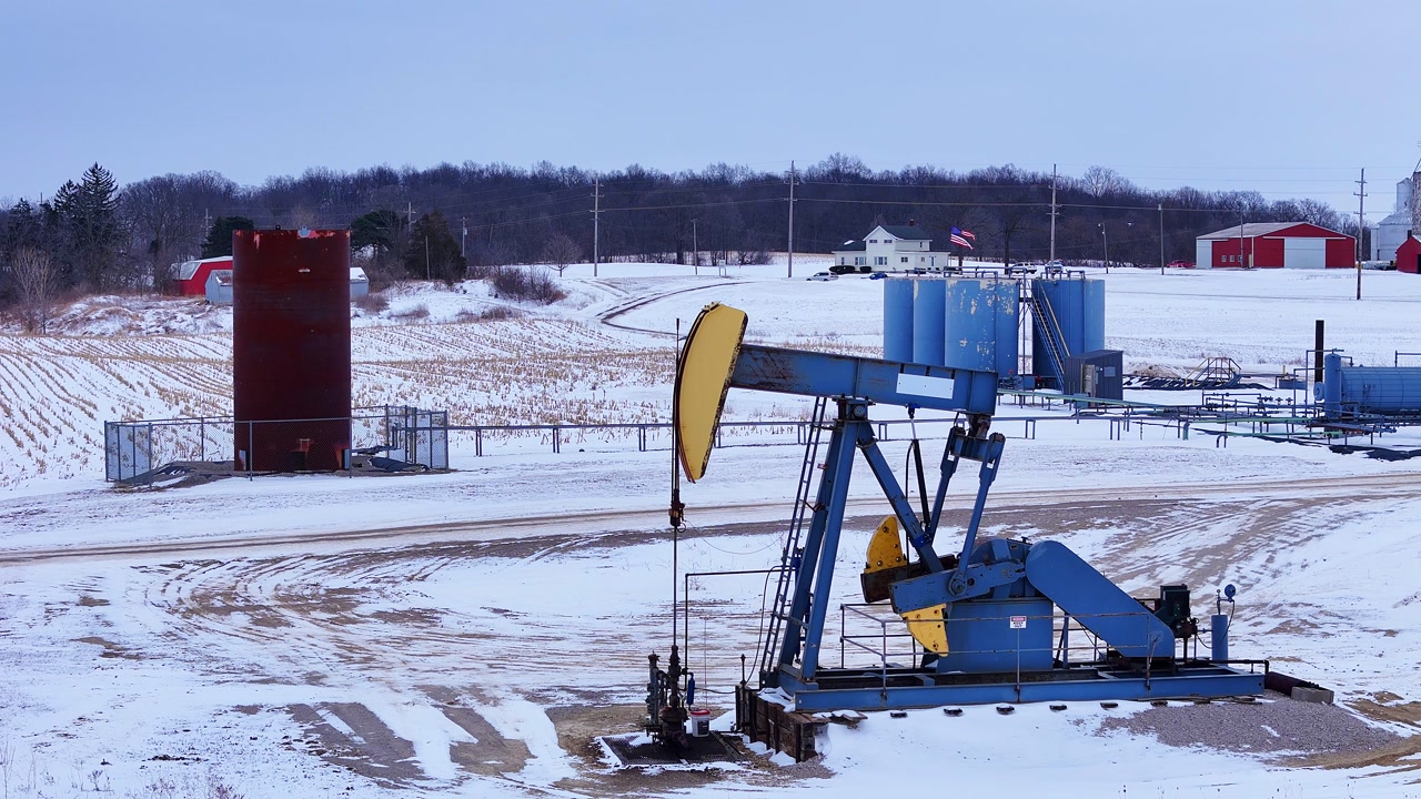 Oil pumpjack actively working to extract crude oil, showing energy production in winter, southeast Michigan, USA