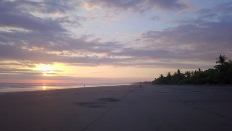 Low-flying-drone-shot-on-beach-in-Costa-Rica-during-colorful-sunset