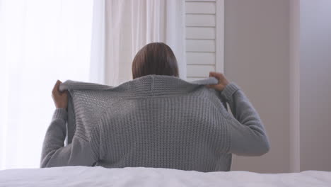 sad young woman looking out of window wearing underwear getting dressed