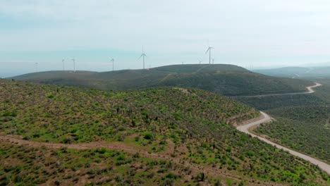 Paso-Elevado-De-Drones-Carretera-De-Montaña-Que-Lleva-Molinos-De-Viento-En-La-Cima-De-Una-Colina-Boscosa,-Paisaje-Escénico,-Chile