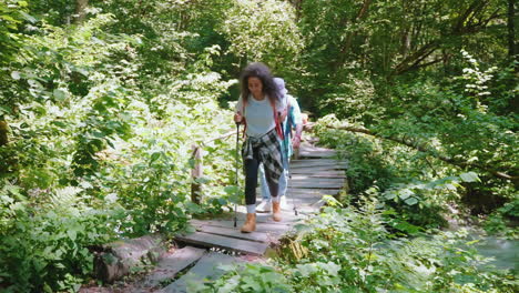 woman hiking on a wooden bridge through a forest