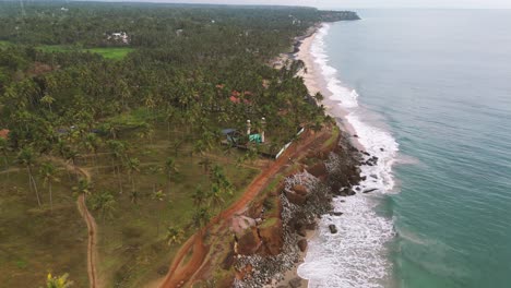 Vista-Aérea-De-Una-Mezquita-Rodeada-De-Cocoteros-En-Un-Acantilado-Junto-Al-Mar-De-Varkala,-Región-De-Kerala,-Sur-De-La-India