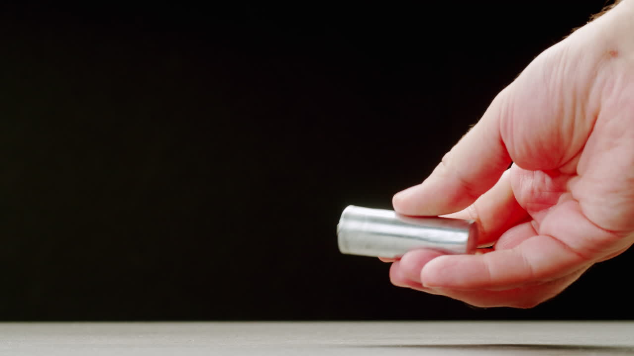 Silver batteries AA and AAA in hands on black background close-up. Double-A battery is a standard size single cell cylindrical dry battery. Batteries are common in portable electronic devices. An AA battery is composed of a single electrochemical cell that may be either a primary battery or a rechar
