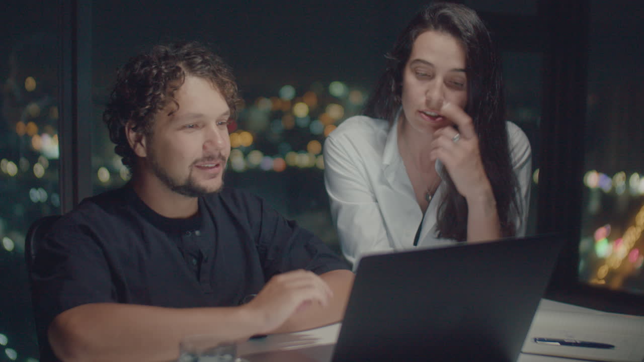 European couple discuss behind laptop
