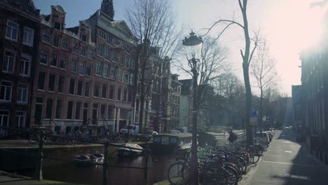 canal vacío de amsterdam en un frío día de invierno con casas y sol dando un destello de lente