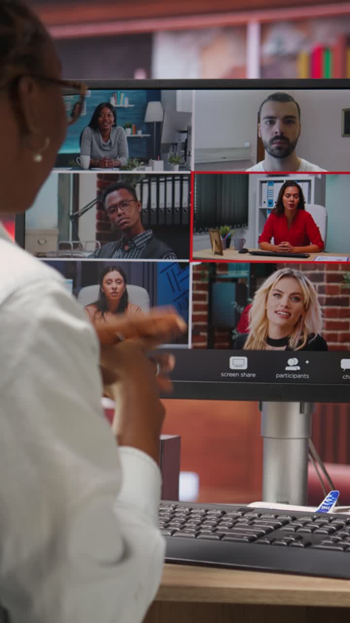 Vertical video Employee greeting coworkers during videocall from home desk