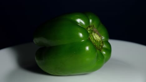 pimienta verde ampliada mientras se coloca en el plato blanco