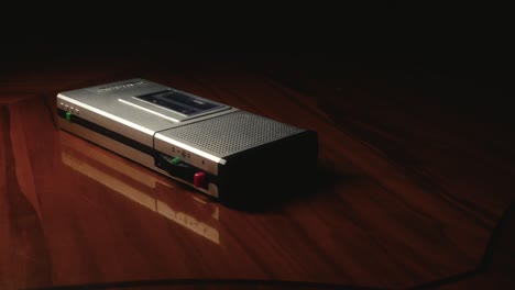 slow movement around a cassette dictaphone lying on a polished table top