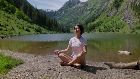 brunette woman making yoga exercise in swiss mountains in front of lake. sunny summer day in peaceful area of nature. close up.