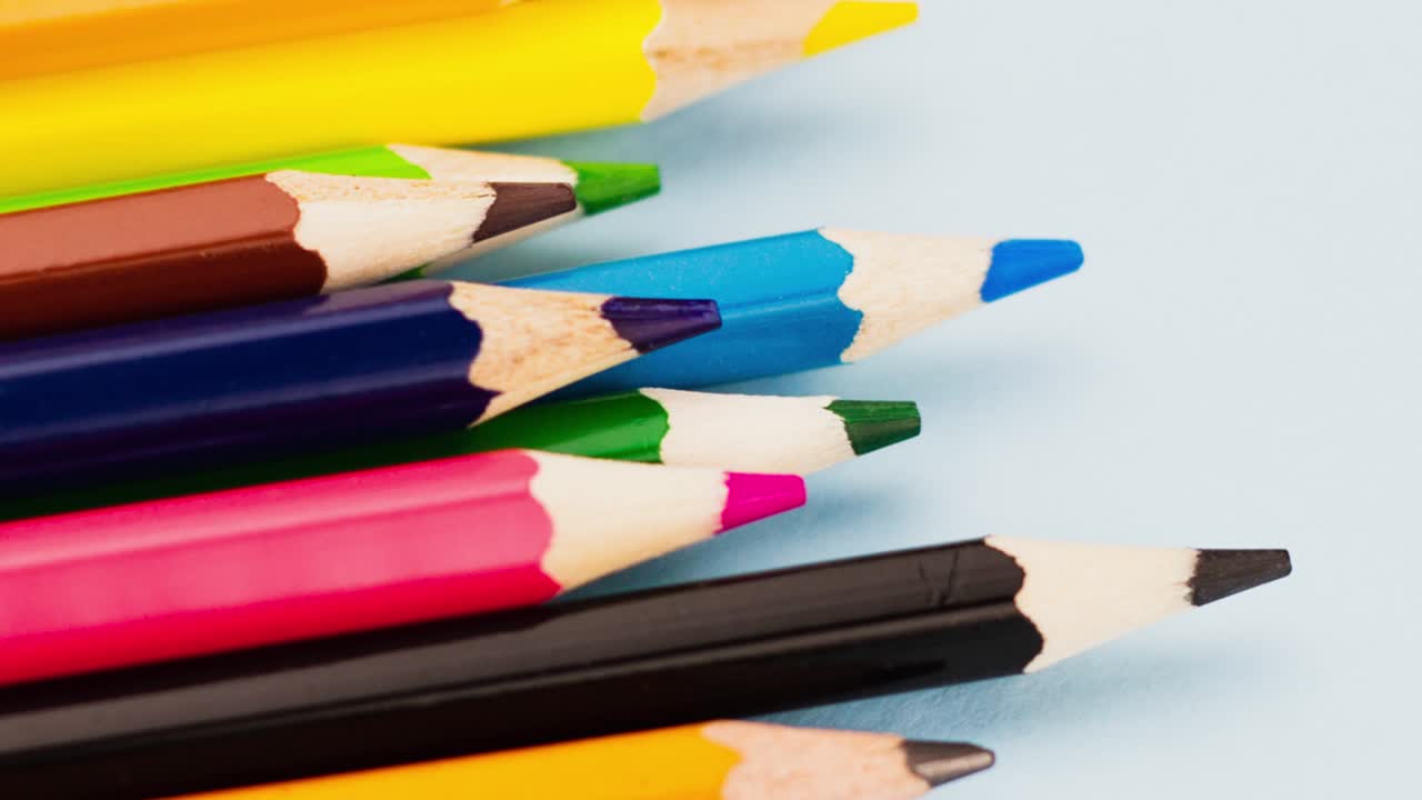 a group of multi-colored colored pencils lie on a gray background close-up, slow motion 4k.