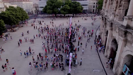 Drohnen-Neigen-Sich-Tagsüber-Von-Den-Arenen-Von-Nîmes-Herunter,-Wenn-Menschen-Schlange-Stehen,-Um-Zurückzukehren