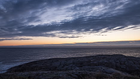 time lapse shot of clouds moving above a rocky coast and the skagerrak sea, at dusk, on justoya island, in aust agder, norway