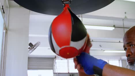 hombre mayor golpeando la bolsa de velocidad en el estudio de fitness 4k