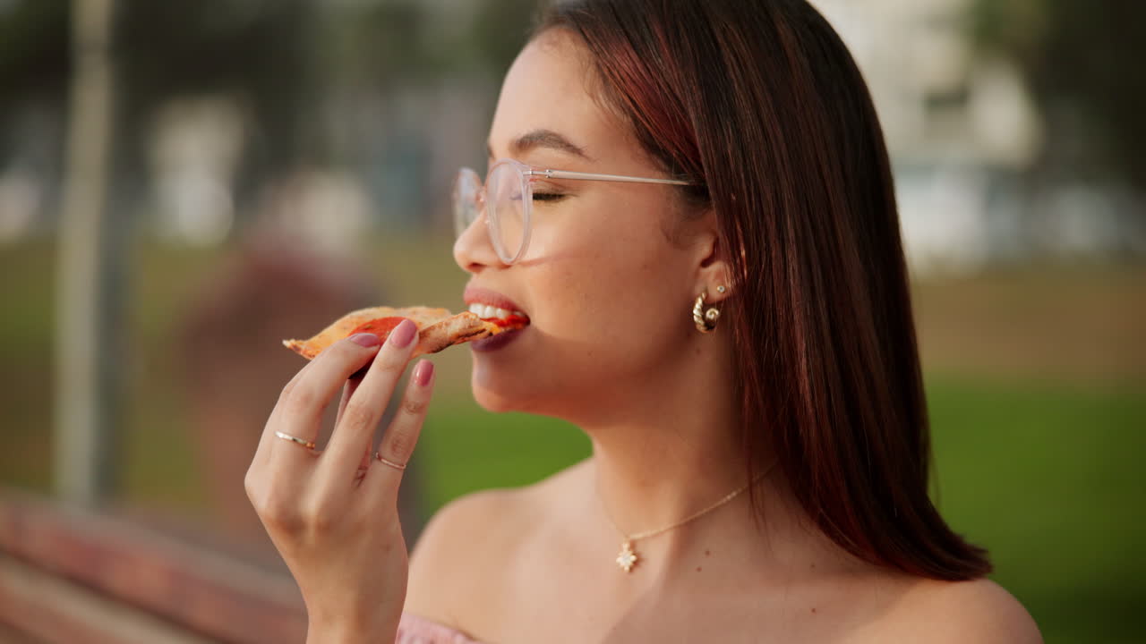 A woman eating pizza outdoors