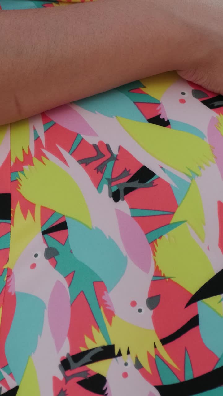 Close-up of a person's hand on a colorful patterned shirt