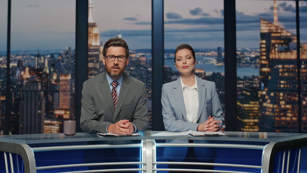 dos locutores de noticias sonriendo transmitiendo noticias en el canal de medios de televisión de primer plano