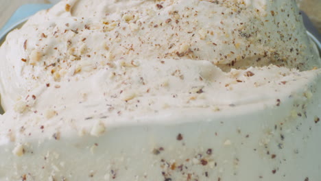 A close-up of a creamy hazelnut ice cream with hazelnut pieces falling on it. A camera shot that highlights texture, contrast, and deliciousness.